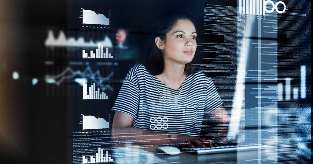 A young female developer focuses intently on the on-screen data in front of her.