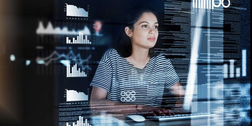 A young female developer focuses intently on the on-screen data in front of her.
