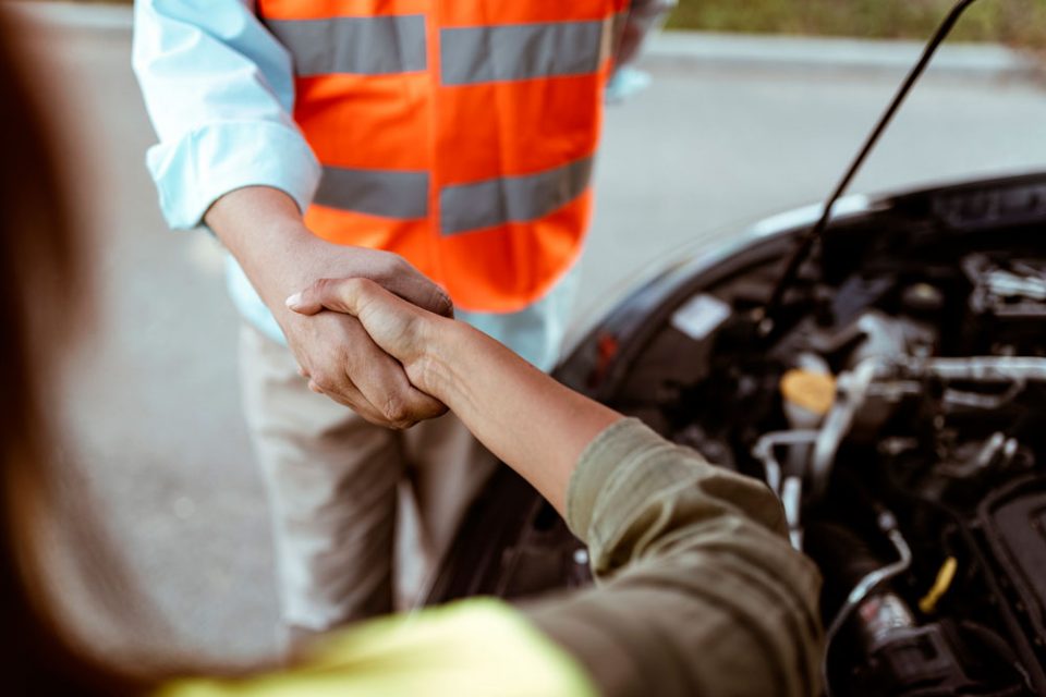 People shaking hands over vehicle engine.  Image supplied by Tracker.