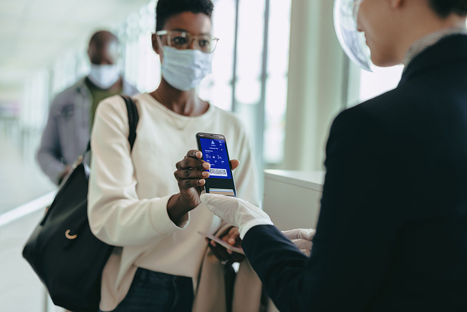 A female traveller at an airport shows her electronic boarding pass to an airline worker at a boarding gate.