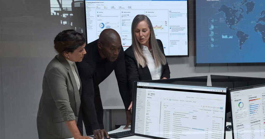 Three security professionals standing at a computer monitor.