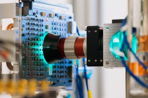 En närbild visar blåaktigt ljus som glöder genom en lins omgiven av kablar, kablar och annan datorhårdvara.