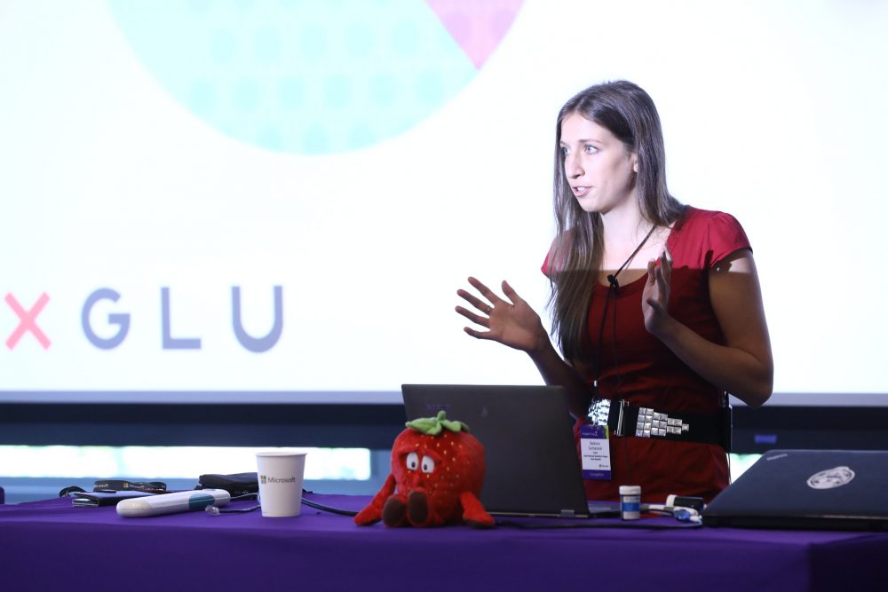 Barbora Suchanova stands behind a laptop, giving a presentatiom