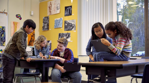 Students working on laptops and other devices