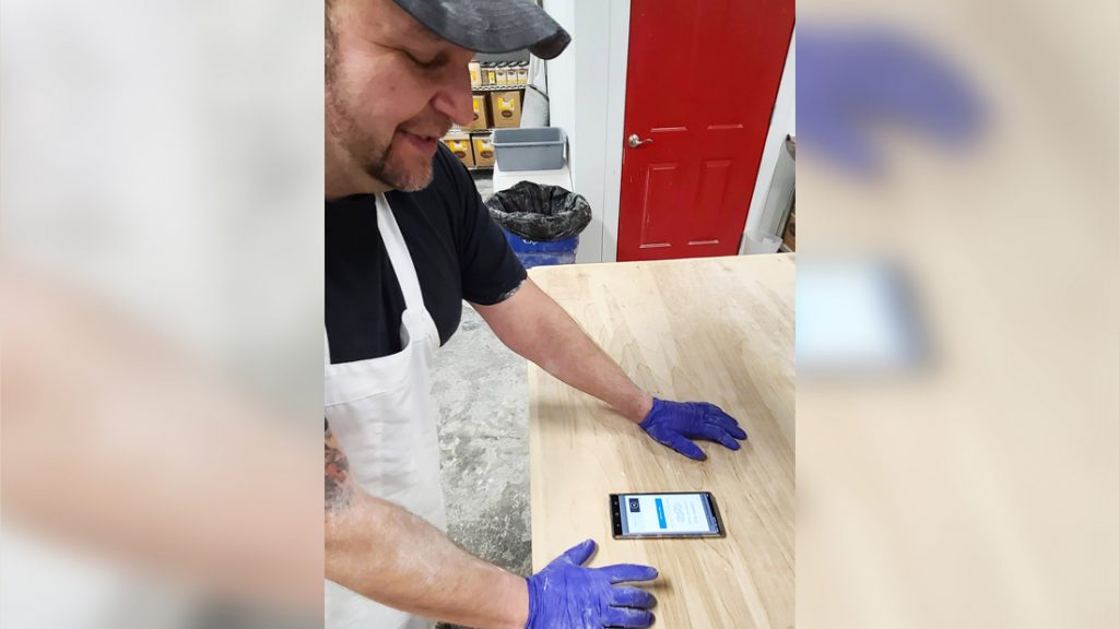 Juan Servin studies his phone at work