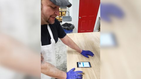 Juan Servin studies his phone at work