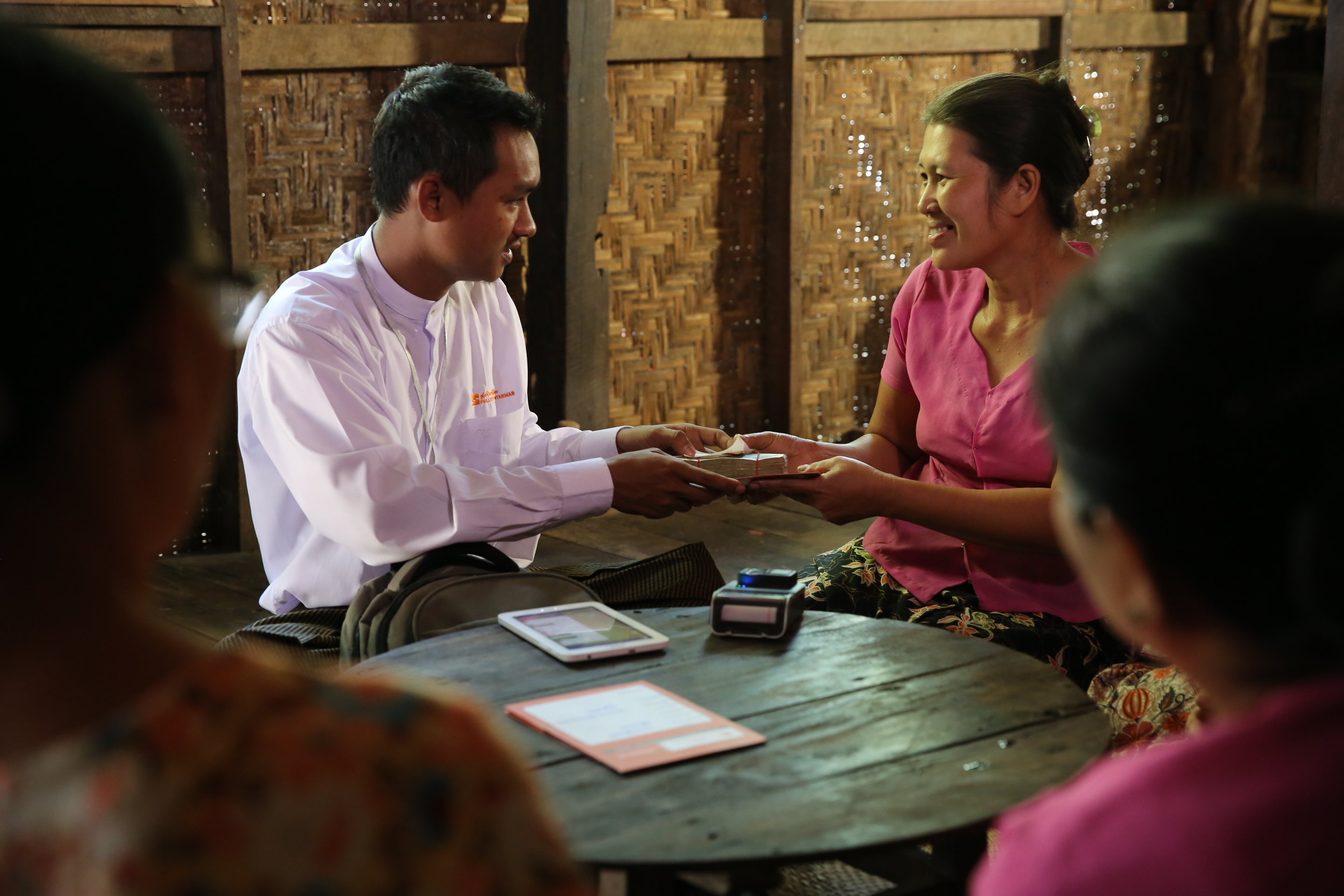 Fullerton Myanmar loan officer Min Thu, left, meets with Win Win Soe, who received a microfinance loan that helped her open a factory that makes noodle snacks.