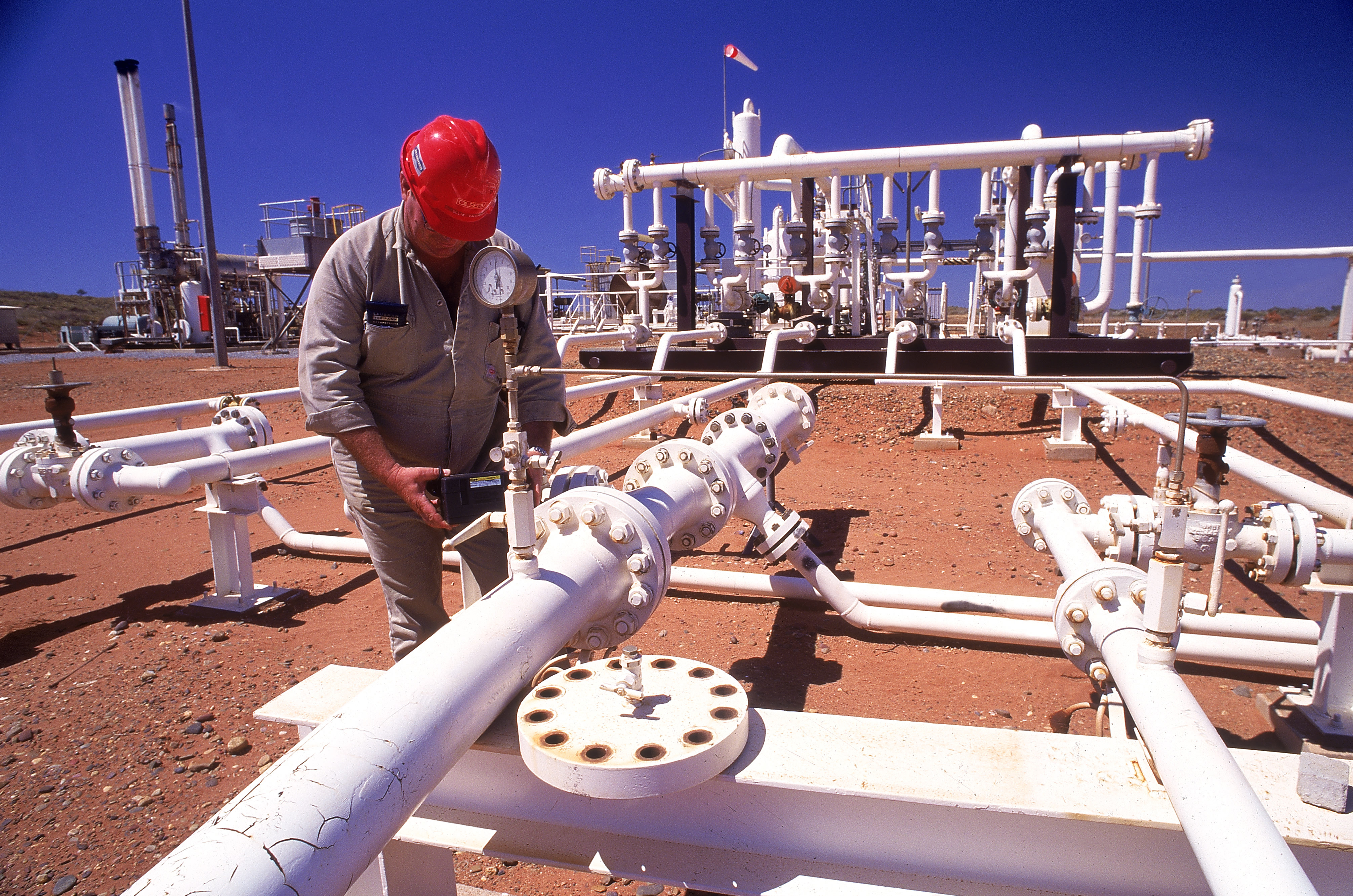 Photo of worker inspecting vales on pipes at gas plant