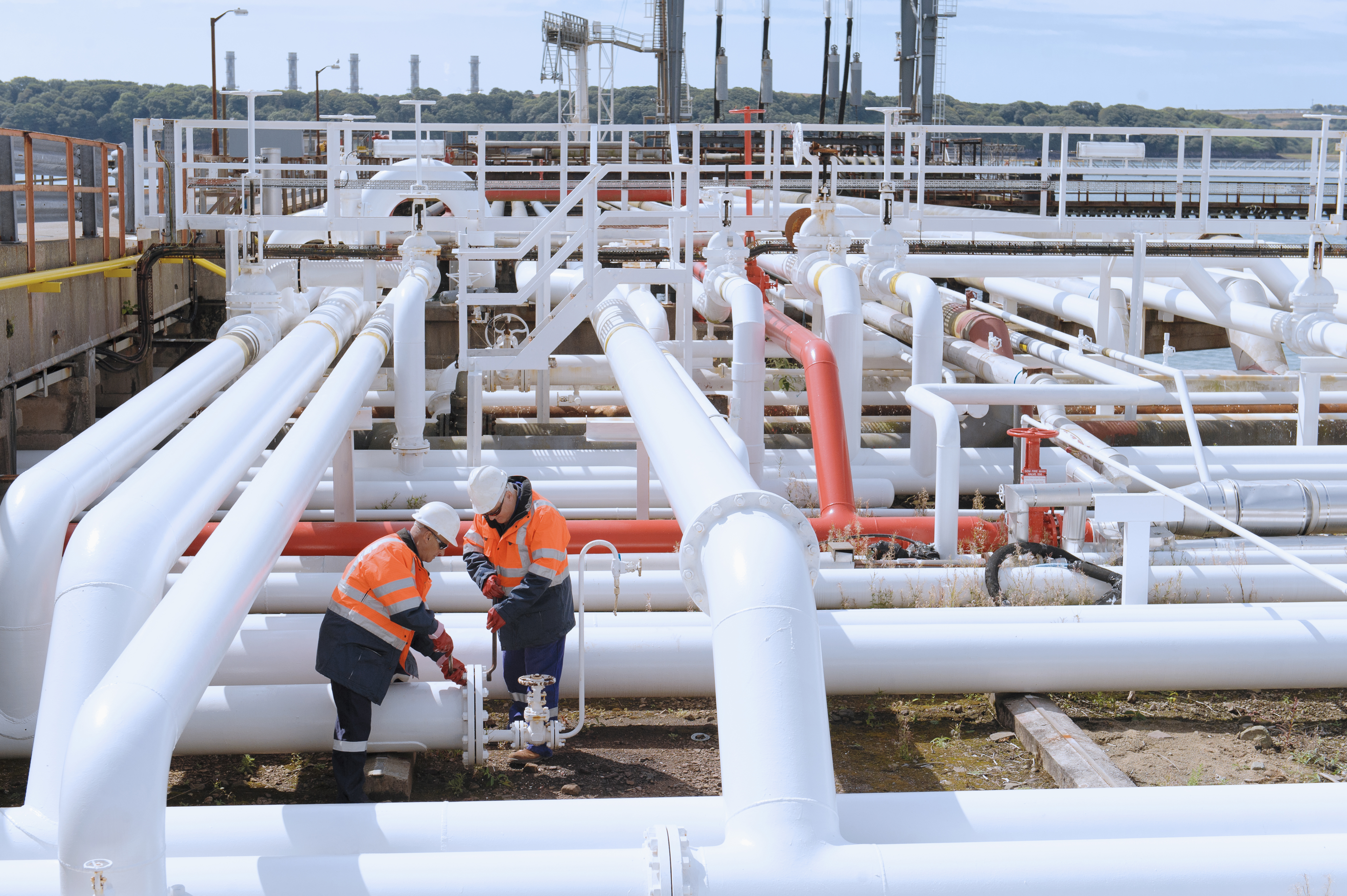 Photo of two male workers tightening bolts on pipe