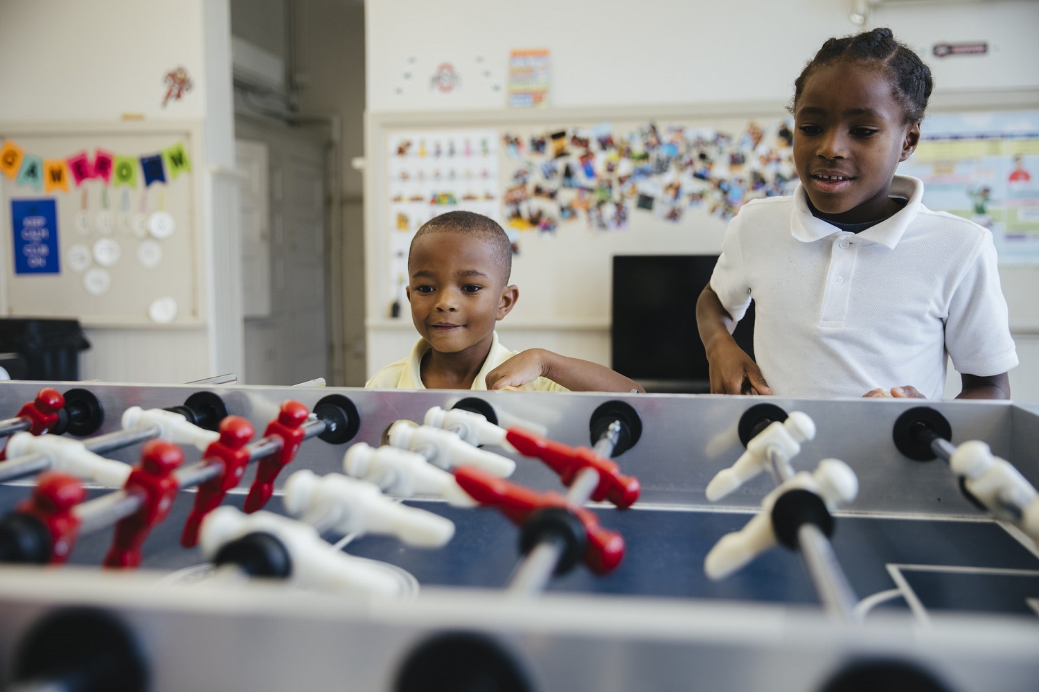Two young boys play foosball