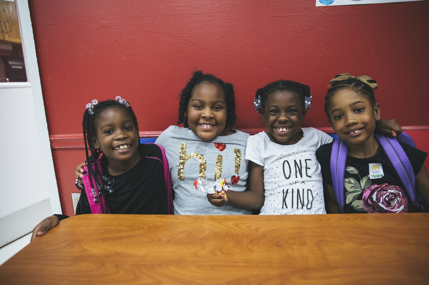 Four young girls smile while sitting together