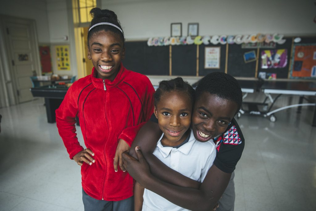 Siblings Dave-Yonna, Johshawn and Davin smile and hug each other