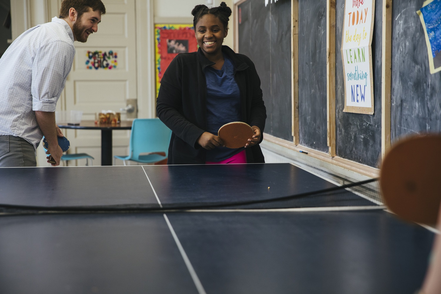 Man and girl smile while playing ping pong