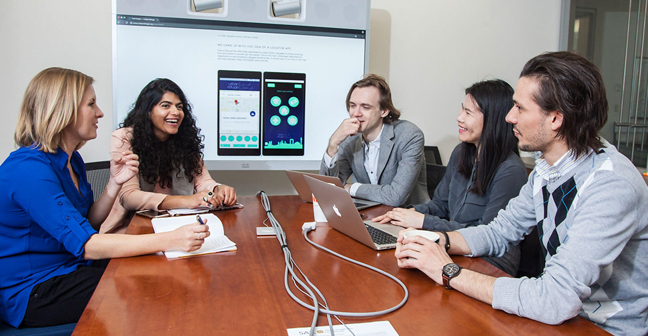 Small group of people smile and work together at a conference table