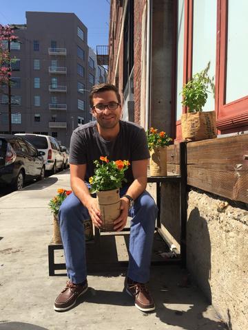 Portrait of man (Chad Corzine) holding planter of flowers