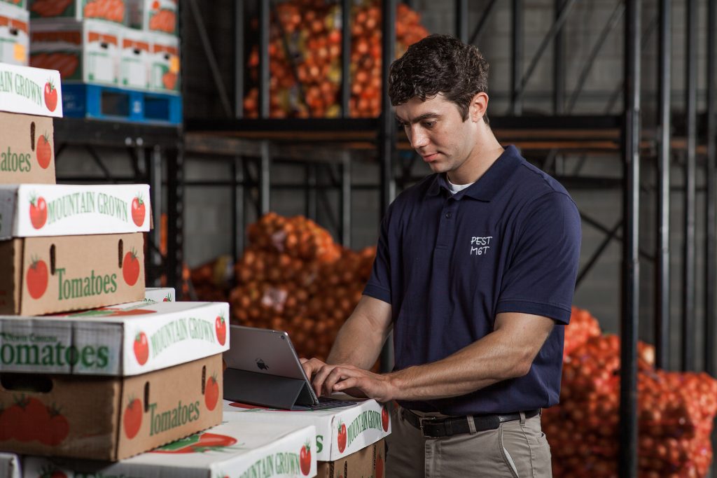 A pest control technician checks RMS data on his laptop at a food processing plant.