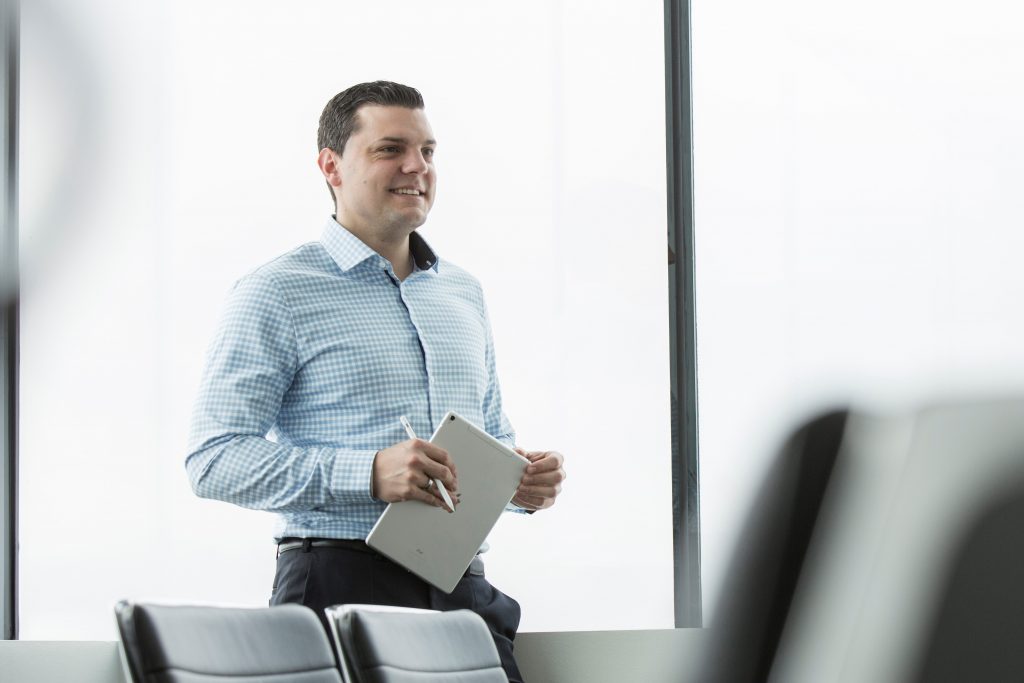 tapio co-founder Julian Spöcker stands in a conference room holding a pad and pen.
