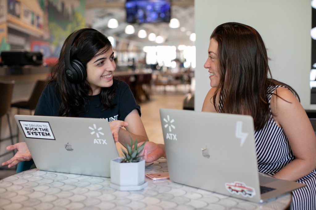Two women work together behind laptops