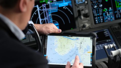 A Norwegian Air Shuttle pilot views a map on a digital device.