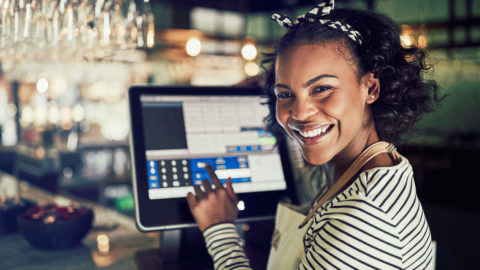 A waitress uses a point-of-sale terminal.