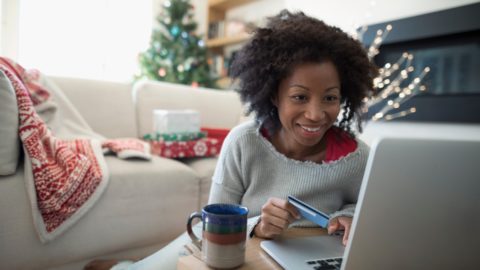 Smiling woman with credit card in front of laptop screen