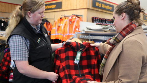 A sales associate helps a customer at a farm supply store.