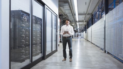 A man works on a tablet device in a data warehouse.