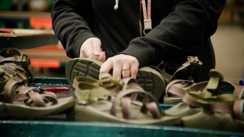 An employee's hands are shown digging into a pile of sandals.