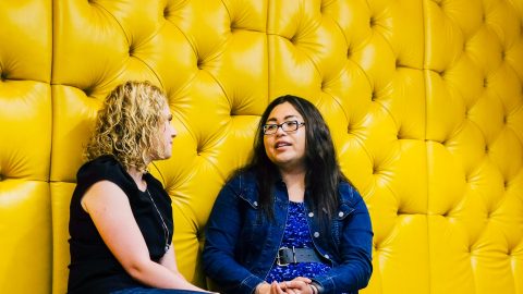 Two people sitting on a yellow couch