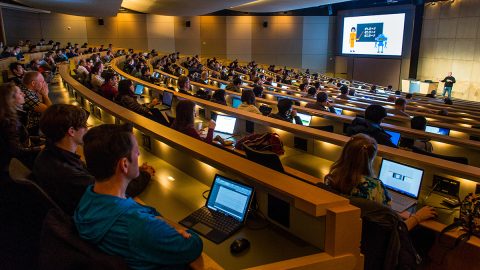 Several students in an auditorium watching a trainer speak