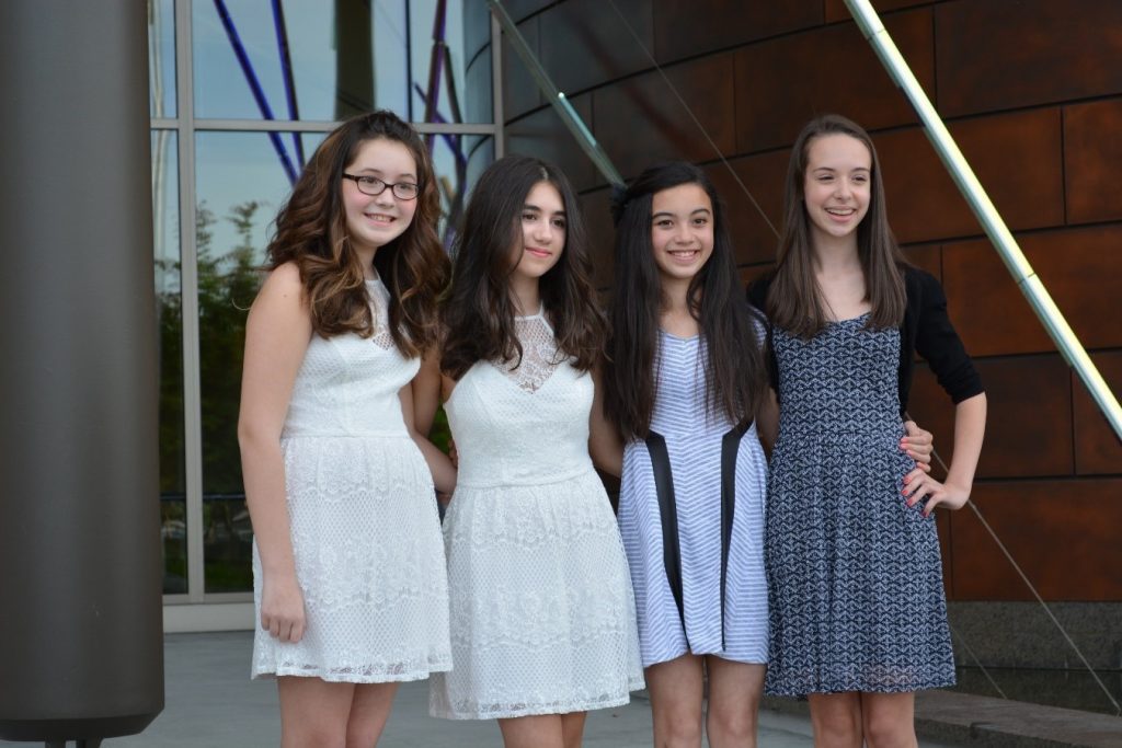 Four young teen girls smiling with arms interlaced