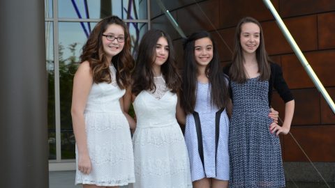 Four young teen girls smiling with arms interlaced