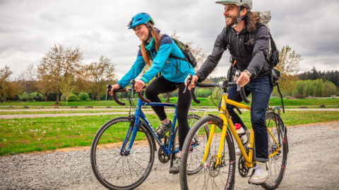 Two people ride bikes on a dirt trail