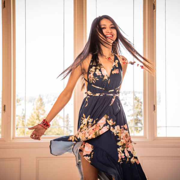 A woman in a black dress twirls in front of a window
