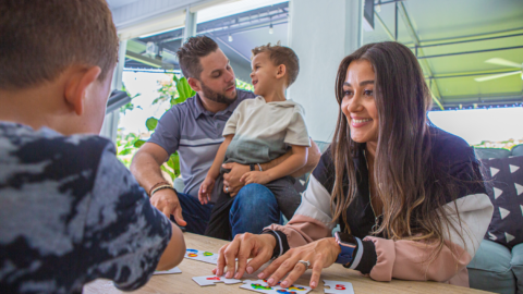 A woman smiles at her son while they play a puzzle