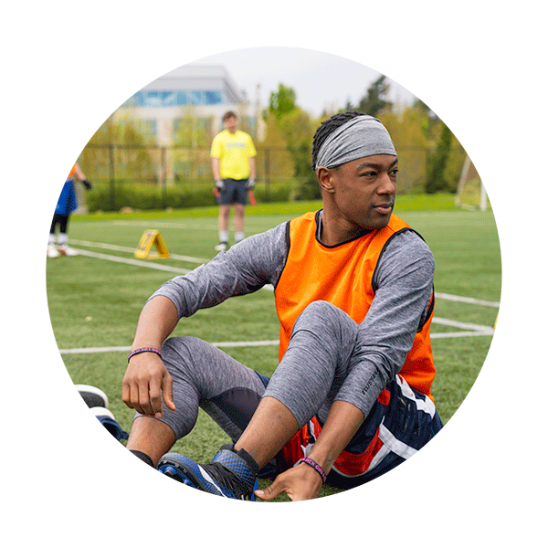 a man in a bright neon shirt stretching for football practice