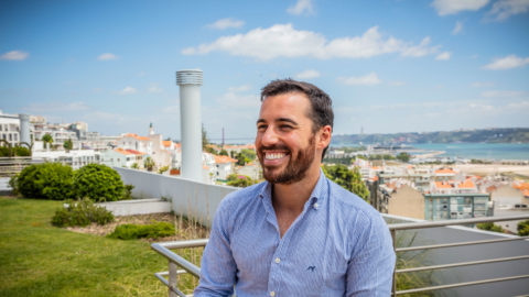 a man smiling with the ocean behind him