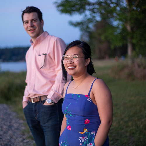 a woman and man stand with their hands in their pockets