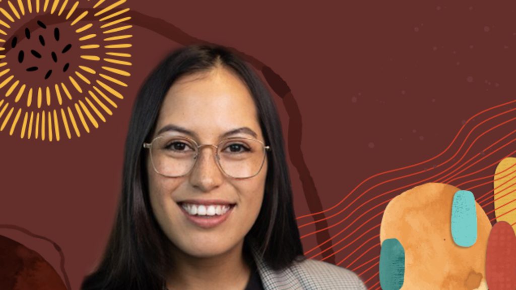 Venus wearing glasses and smiling in front of a brown background with colorful hues.