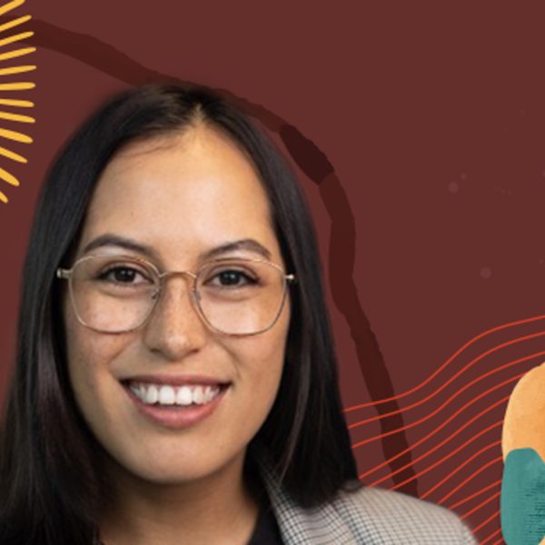 Venus wearing glasses and smiling in front of a brown background with colorful hues.