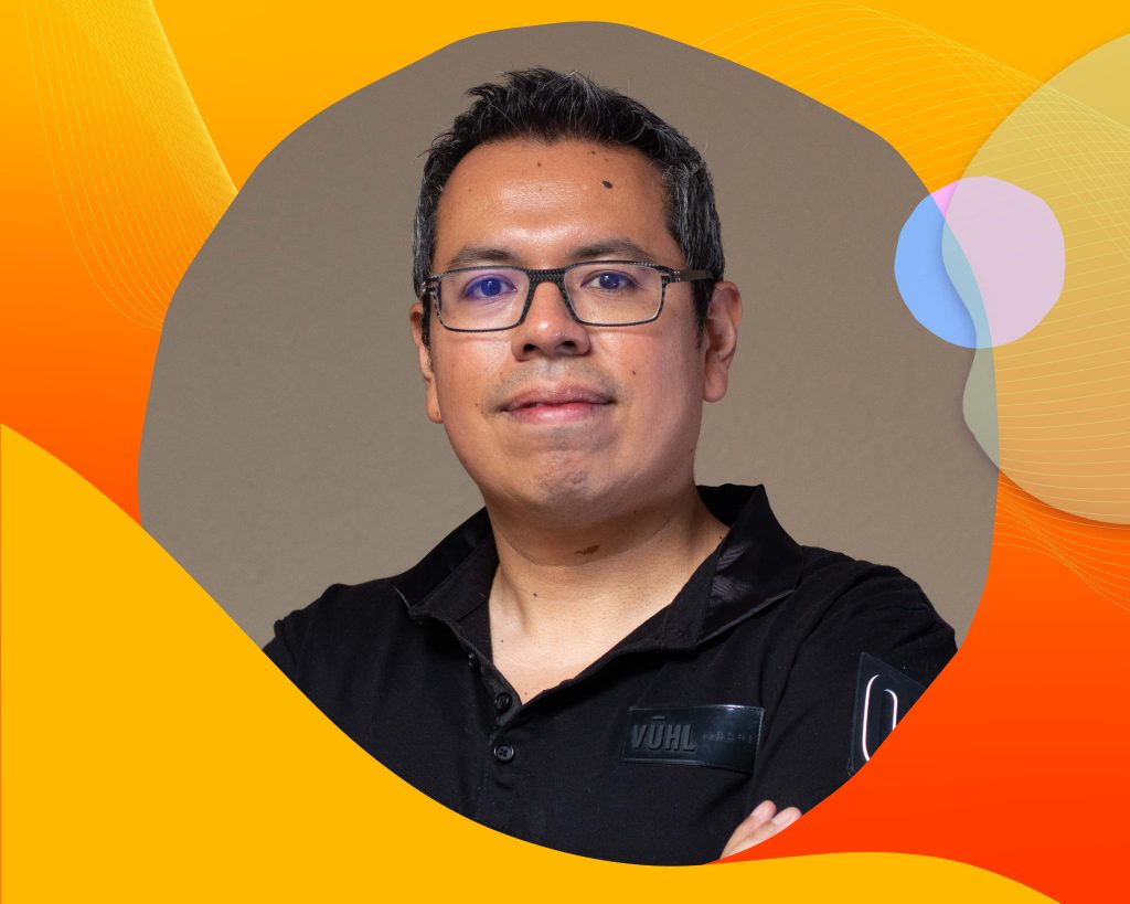 Luis is wearing glasses, smiling in a portrait. He's wearing a black collared shirt.