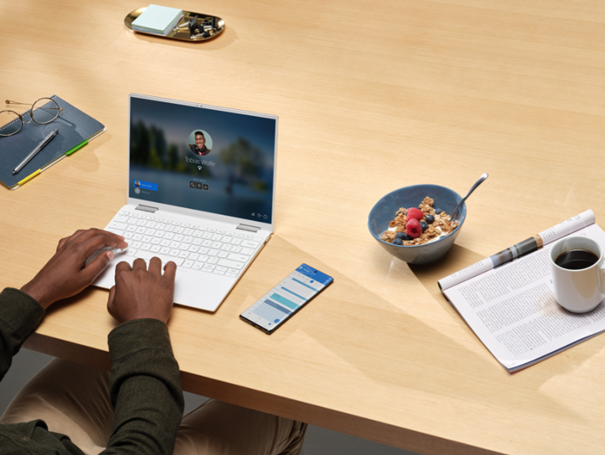 Blick auf einen Arbeitsplatz mit Surface, Smartphone und Frühstücksutensilien