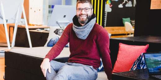 Jan Schenk sitzt im Office und lacht in die Kamera.
