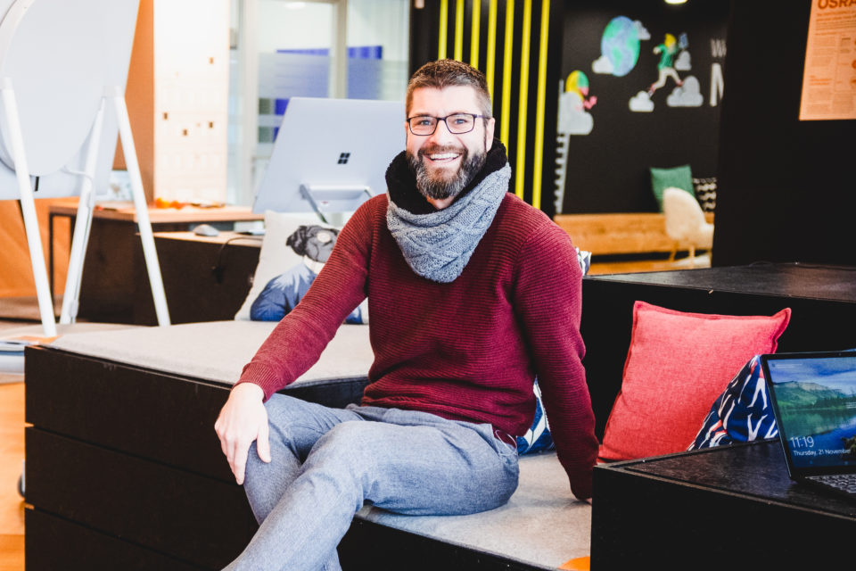 Jan Schenk sitzt im Office und lacht in die Kamera.