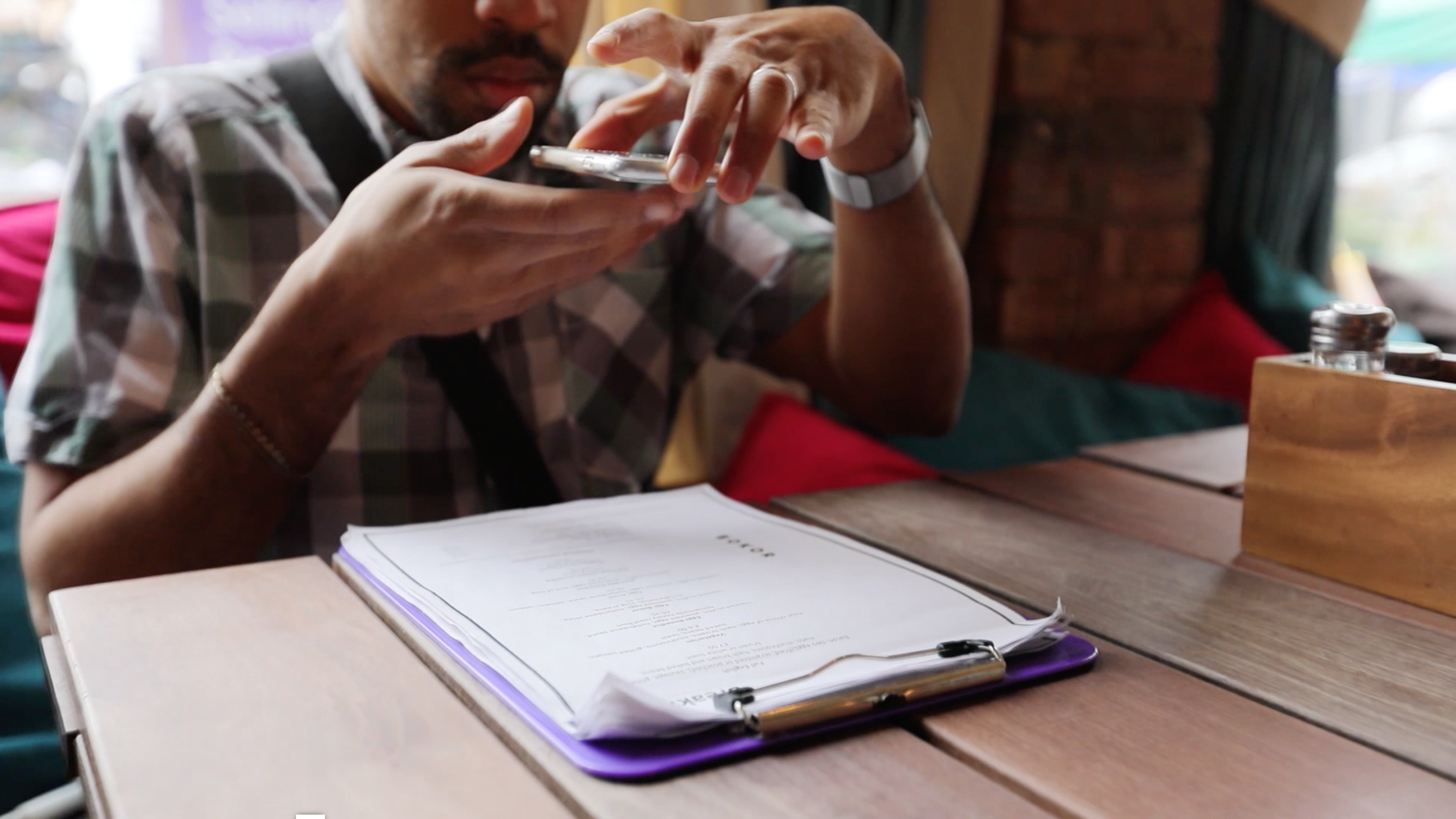 Ein Mann sitzt in einem Restaurant und lässt sich mit Seeing AI die Speisekarte vorlesen