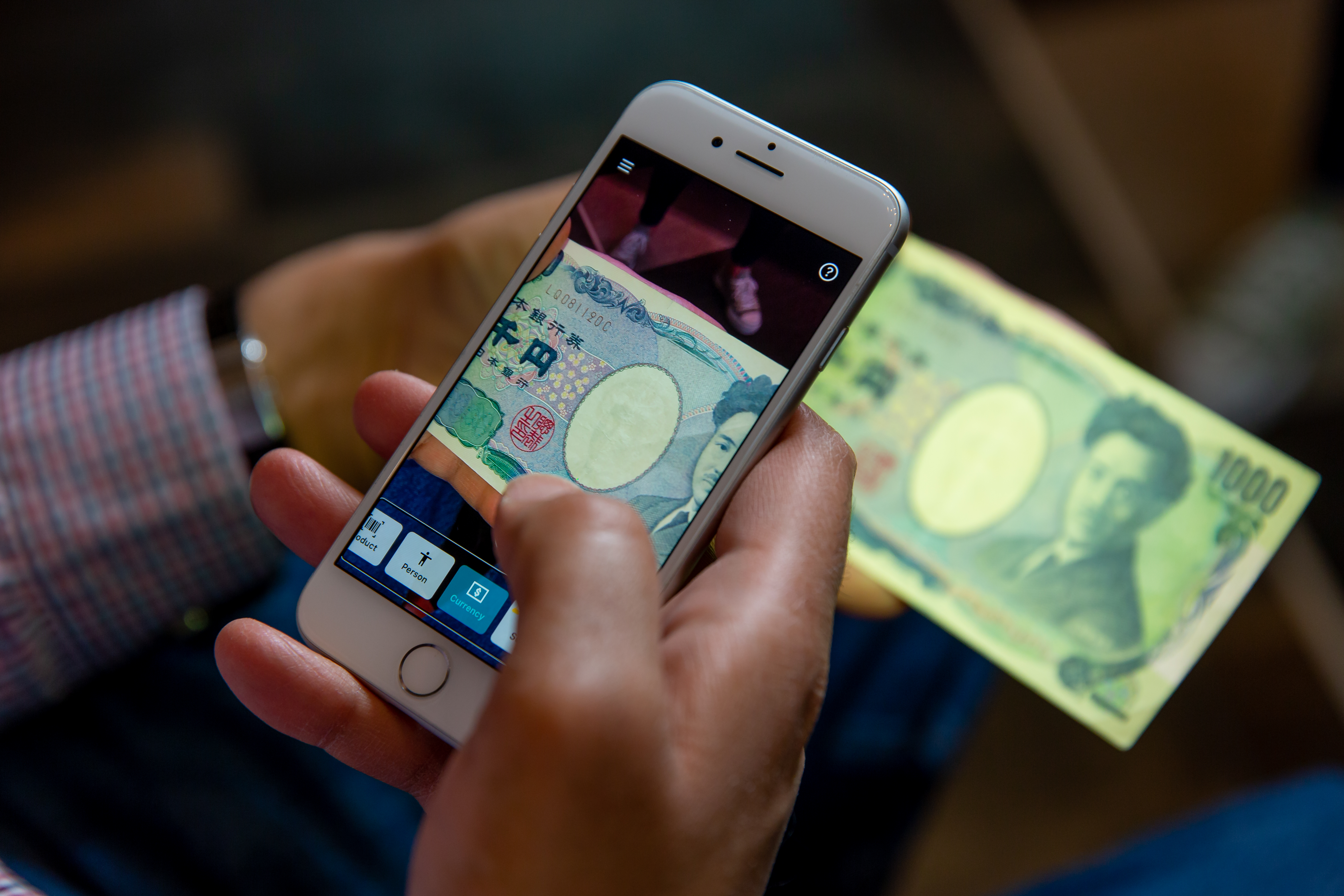 Ein Mann nutzt Seeing AI, um sich den Wert eines Geldscheins vorlesen zu lassen.