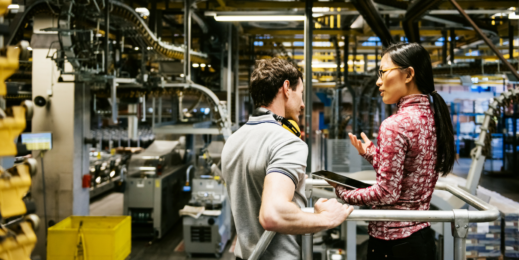 Zwei Personen unterhalten sich in einer Produktionsumgebung.