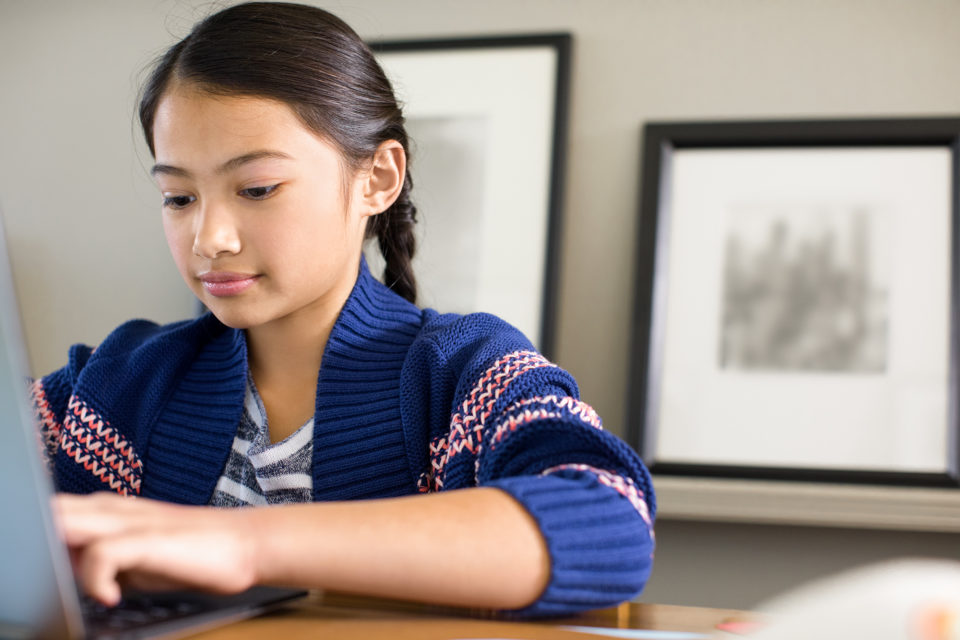 Ein Mädchen lernt an ihrem Laptop zu Hause.