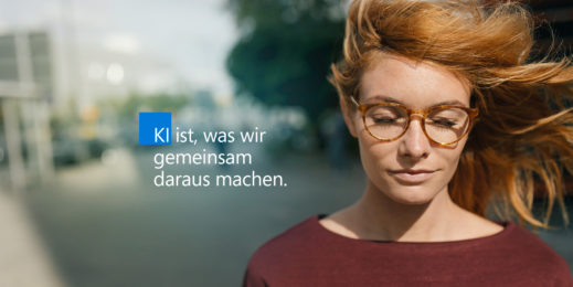 Frau mit wehenden roten Haaren und geschlossenen Augen plus Schriftzug "KI ist, was wir gemeinsam daraus machen"