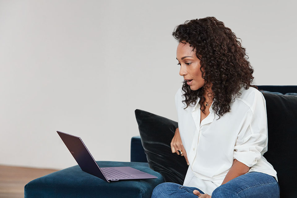 Frau arbeitet von zu Hause und spricht in ihren Laptop.